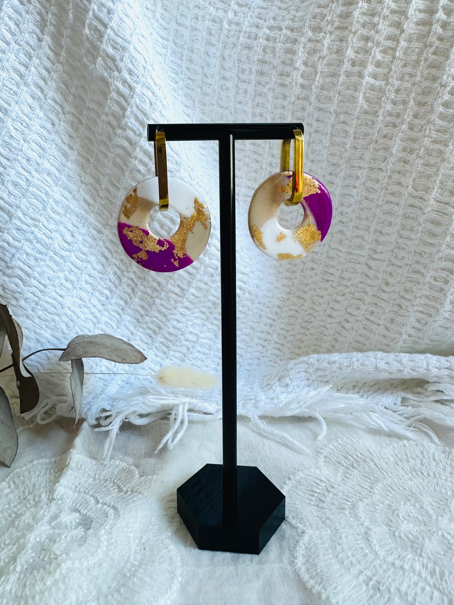 Pendiente donut grande, aro alargado, morado, blanco y beige, con toques dorados.