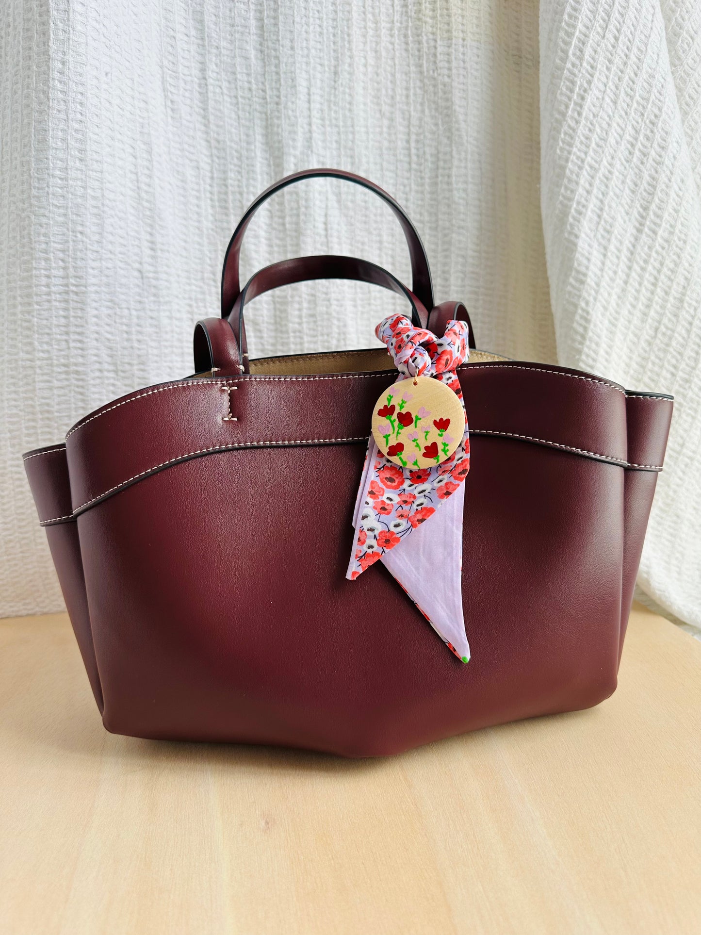 Adorno para bolso flores rojas y fondo lila.