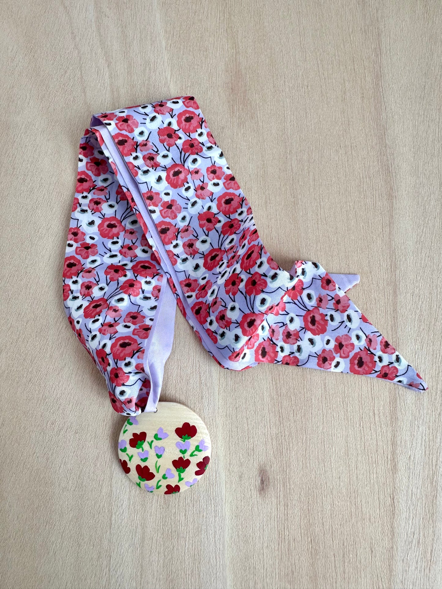 Adorno para bolso flores rojas y fondo lila.