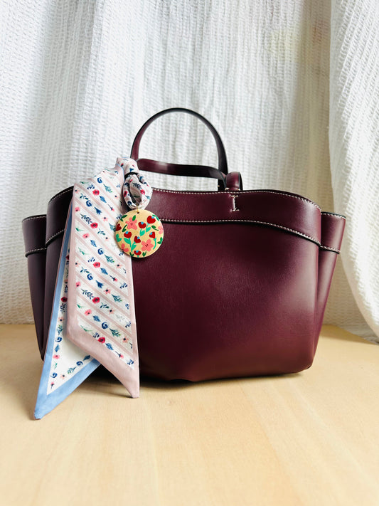 Adorno para bolso en tonos azules, beige y rojizos.