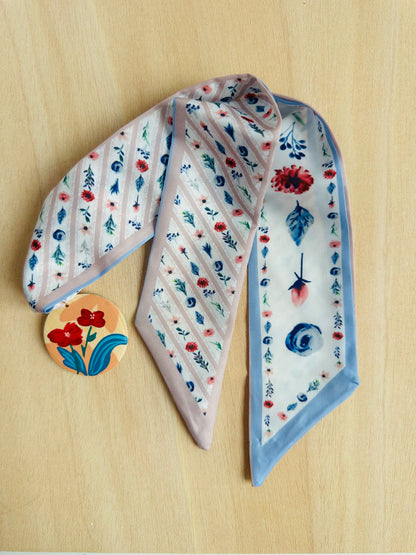 Adorno para bolso en tonos azules, beige y rojizos.