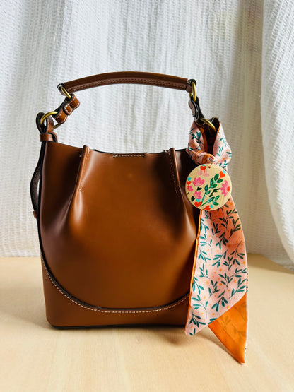 Adorno para bolso rosa con hojitas verdes.